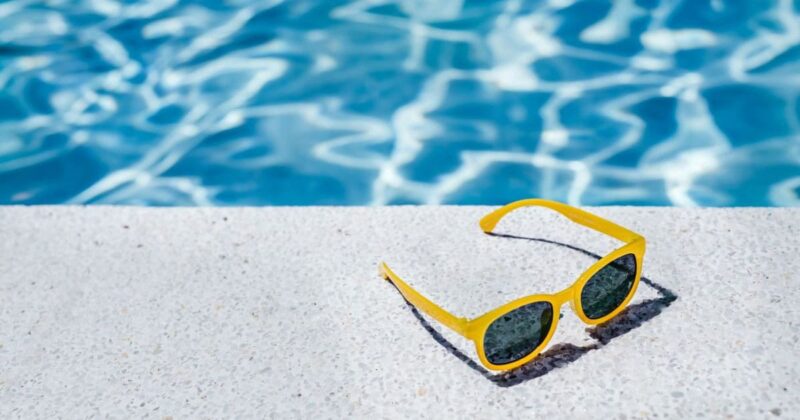 yellow sunglasses on a pool deck in the summer